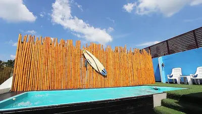 a surfboard on a fence next to a swimming pool at Must Sea Hotel - SHA Hotel in Kata Beach