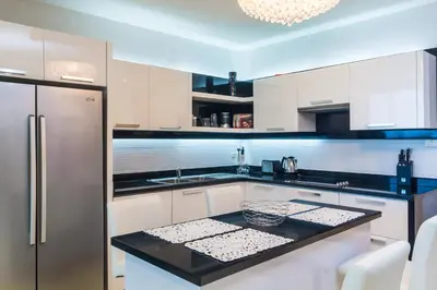 a kitchen with white cabinets and a stainless steel refrigerator at The Palm at Veloche Group by Lofty in Karon Beach