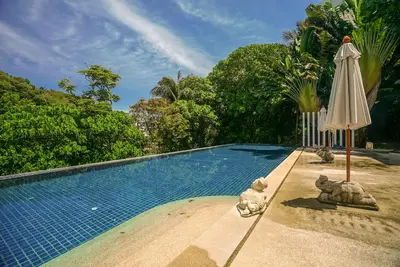 a large swimming pool with an umbrella and a pool at The Palm at Veloche Group by Lofty in Karon Beach