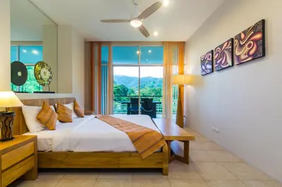 a bedroom with a bed and a large window at The Palm at Veloche Group by Lofty in Karon Beach