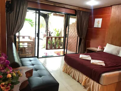 a bedroom with a bed and a couch and a window at Ruan Mai San Ngam Resort - SHA Plus in Nai Yang Beach