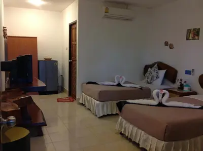 a hotel room with two beds and a flat screen tv at Ruan Mai San Ngam Resort - SHA Plus in Nai Yang Beach