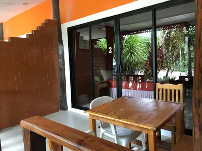 a wooden table and chairs on a patio at Ruan Mai San Ngam Resort - SHA Plus in Nai Yang Beach