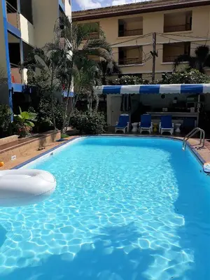 a large swimming pool with chairs and a building at PorterHouse Beach Hotel in Patong Beach