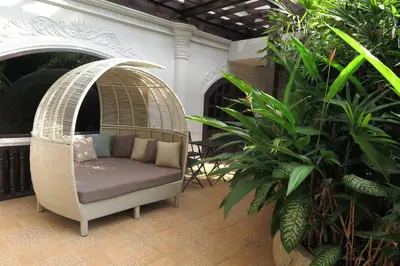 a porch with a rattan chair and some plants at Pearl Hotel Phuket in Phuket Town