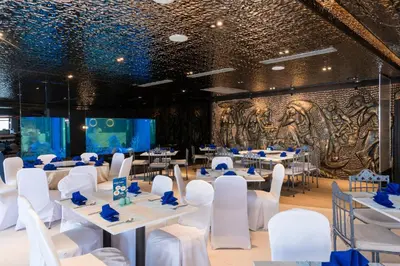 a banquet hall with white tables and chairs and a wall with a mural at Pearl Hotel Phuket in Phuket Town