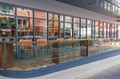 a bar with chairs in a building with windows at Pearl Hotel Phuket in Phuket Town