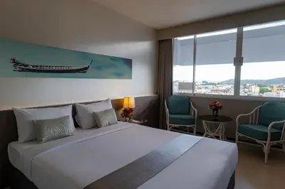 a hotel room with a large bed and two chairs at Pearl Hotel Phuket in Phuket Town
