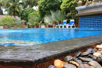 a swimming pool with chairs and rocks next to it at Baan Vanida Garden Resort in Karon Beach
