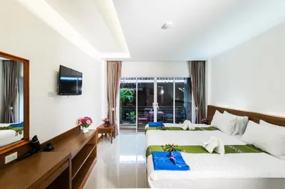 a hotel room with two beds and a television at Baan Vanida Garden Resort in Karon Beach