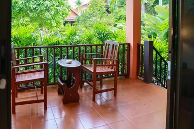 a balcony with two chairs and a table on it at Baan Vanida Garden Resort in Karon Beach