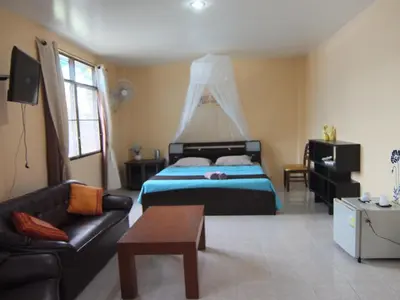a bedroom with a bed and a couch and a table at Similan Hotel in Bang Tao Beach