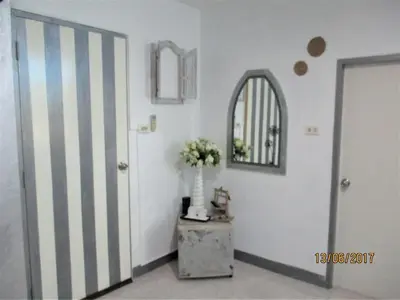 a hallway with a door and a table with a vase of flowers at Similan Hotel in Bang Tao Beach