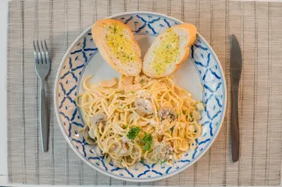 a blue and white plate of pasta with meat and bread at Amarin Hotel Patong in Patong Beach