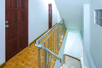 a staircase with a metal railing and a brown door at Mala Hotel in Kata Beach