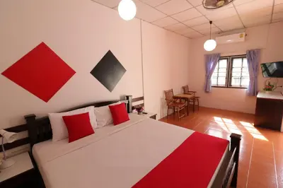 a bedroom with a large bed with red pillows at Baan Nat The Village in Phuket Town