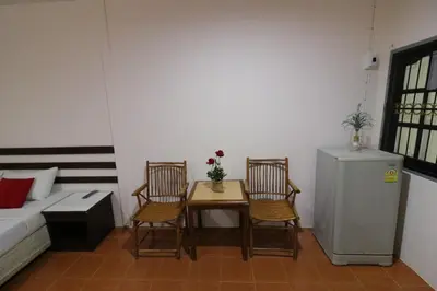 a room with a table and two chairs and a bed at Baan Nat The Village in Phuket Town