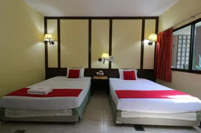 a room with two beds with red and white sheets at Baan Nat The Village in Phuket Town