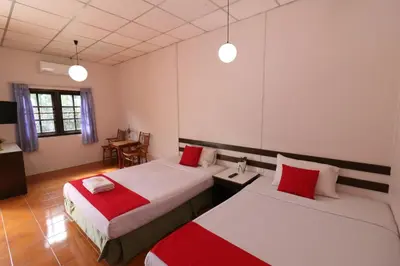 a room with two beds with red and white sheets at Baan Nat The Village in Phuket Town