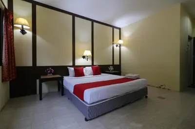 a bedroom with a large bed with red pillows at Baan Nat The Village in Phuket Town
