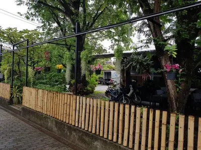 a fence in front of a house with a motorcycle at Baan Nat The Village in Phuket Town
