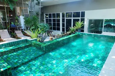 a swimming pool in a house with turquoise water at Benjamas Place Hotel in Rawai Beach