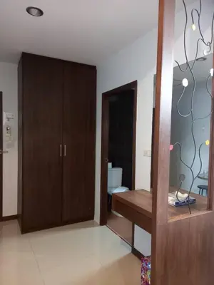a room with a desk and a wooden cabinet at Benjamas Place Hotel in Rawai Beach
