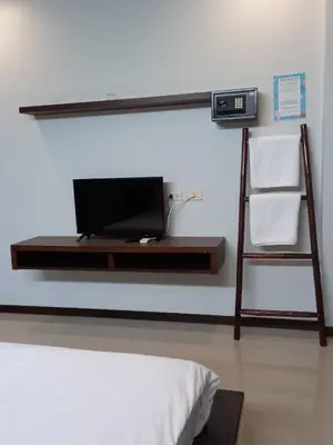 a room with a bed and a tv on a shelf at Benjamas Place Hotel in Rawai Beach