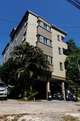 a tall building with a palm tree in front of it at Benjamas Place Hotel in Rawai Beach