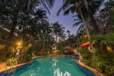 a pool at a resort with palm trees at night at The Viridian Resort Patong in Patong Beach