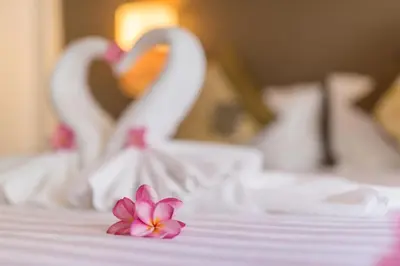 two white swans with a pink flower on a bed at The Viridian Resort Patong in Patong Beach
