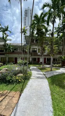 a walkway in front of a building with palm trees at The Viridian Resort Patong in Patong Beach
