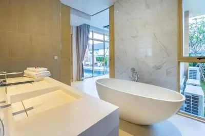 a bathroom with a large white tub and a sink at Himmapana Villas - SHA Extra Plus in Kamala Beach