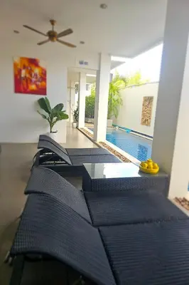 a row of black chairs in a room with a swimming pool at One World One Home Naiharn Hotel in Rawai Beach