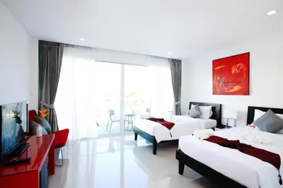 a hotel room with two beds and a television at One World One Home Naiharn Hotel in Rawai Beach