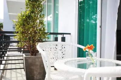 a table and chairs on a balcony with a flower in a vase at One World One Home Naiharn Hotel in Rawai Beach