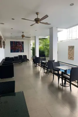 a dining room with tables and chairs and a ceiling fan at One World One Home Naiharn Hotel in Rawai Beach