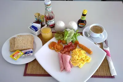 a table with two plates of breakfast foods and a cup of coffee at One World One Home Naiharn Hotel in Rawai Beach