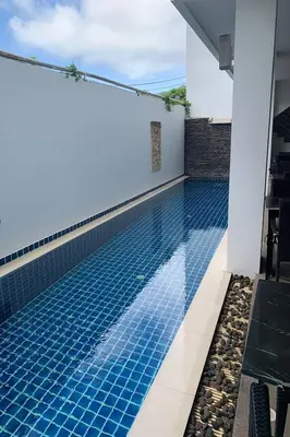 a swimming pool next to a house at One World One Home Naiharn Hotel in Rawai Beach