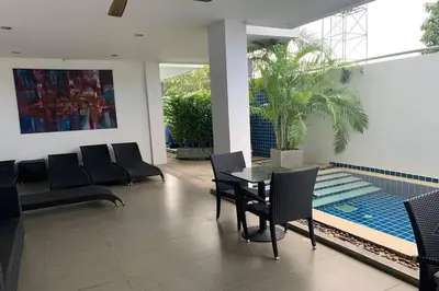 a dining room with a table and chairs and a pool at One World One Home Naiharn Hotel in Rawai Beach