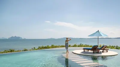 a man standing on the edge of a pool at a resort at The Naka Island, a Luxury Collection Resort & Spa, Phuket in Ko Naka