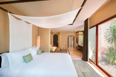 a bedroom with a white bed and a large window at The Naka Island, a Luxury Collection Resort & Spa, Phuket in Ko Naka