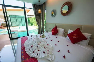 a bedroom with a white bed with red pillows at Good Night Pool Villa Phuket - SHA Plus in Phuket Town