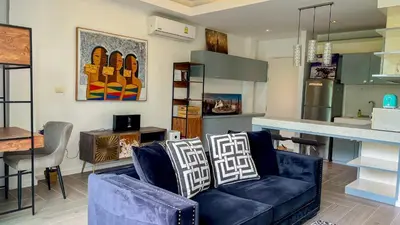 a living room with a blue couch and a kitchen at Great view in 81sqm top floor space in Kamala in Kamala Beach