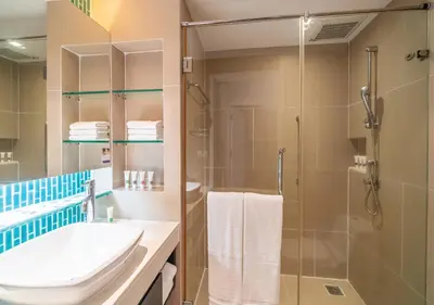 a bathroom with a shower and a sink and a toilet at Radisson Resort and Suites Phuket in Kamala Beach