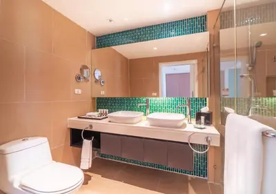 a bathroom with two sinks and a toilet and a mirror at Radisson Resort and Suites Phuket in Kamala Beach