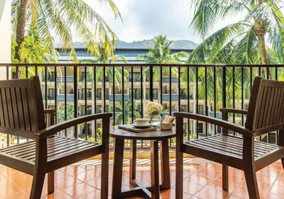 a table and two chairs on a balcony with a view at Radisson Resort and Suites Phuket in Kamala Beach