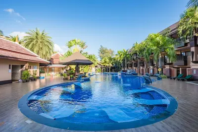 a large swimming pool in a resort with palm trees at Princess Kamala Beachfront Hotel - SHA Extra Plus in Kamala Beach