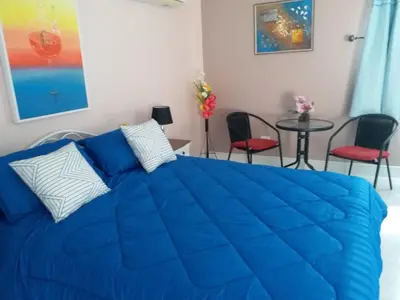 a blue bed in a room with chairs and a table at Résidence Chez Nous Phuket in Rawai Beach