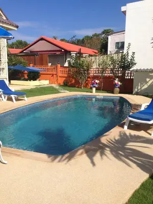 a swimming pool with two chairs and a house at Résidence Chez Nous Phuket in Rawai Beach